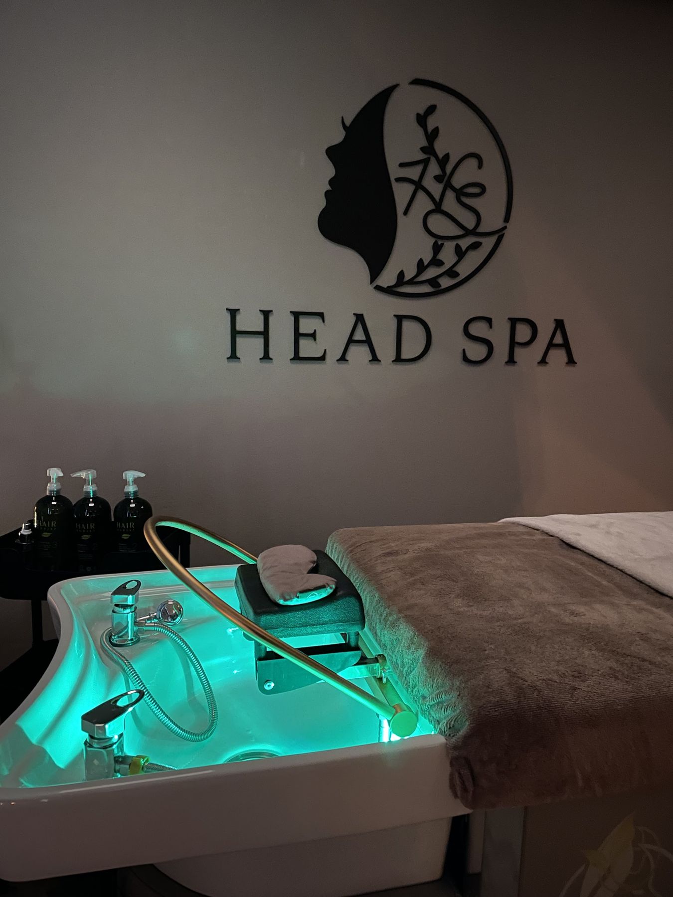 Het logo van Headspa Doetinchem op de muur boven de verlichte waskom