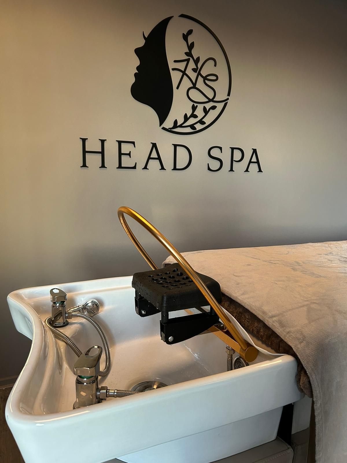 De witte waskom met de gouden waterboog onder het logo van Headspa Doetinchem